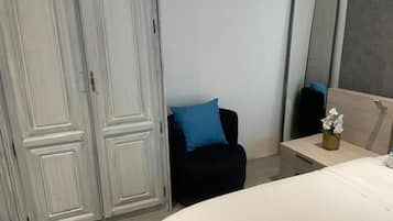 Un dormitorio con cama, una silla, una mesita de noche, un espejo y un armario.