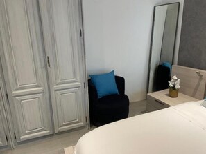 Un dormitorio con cama, una silla, una mesita de noche, un espejo y un armario.