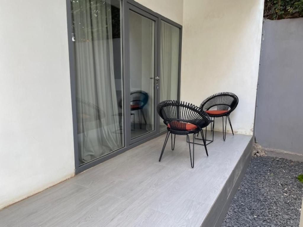 Un pequeño espacio al aire libre con dos sillas y una puerta de cristal que da a un área cubierta.