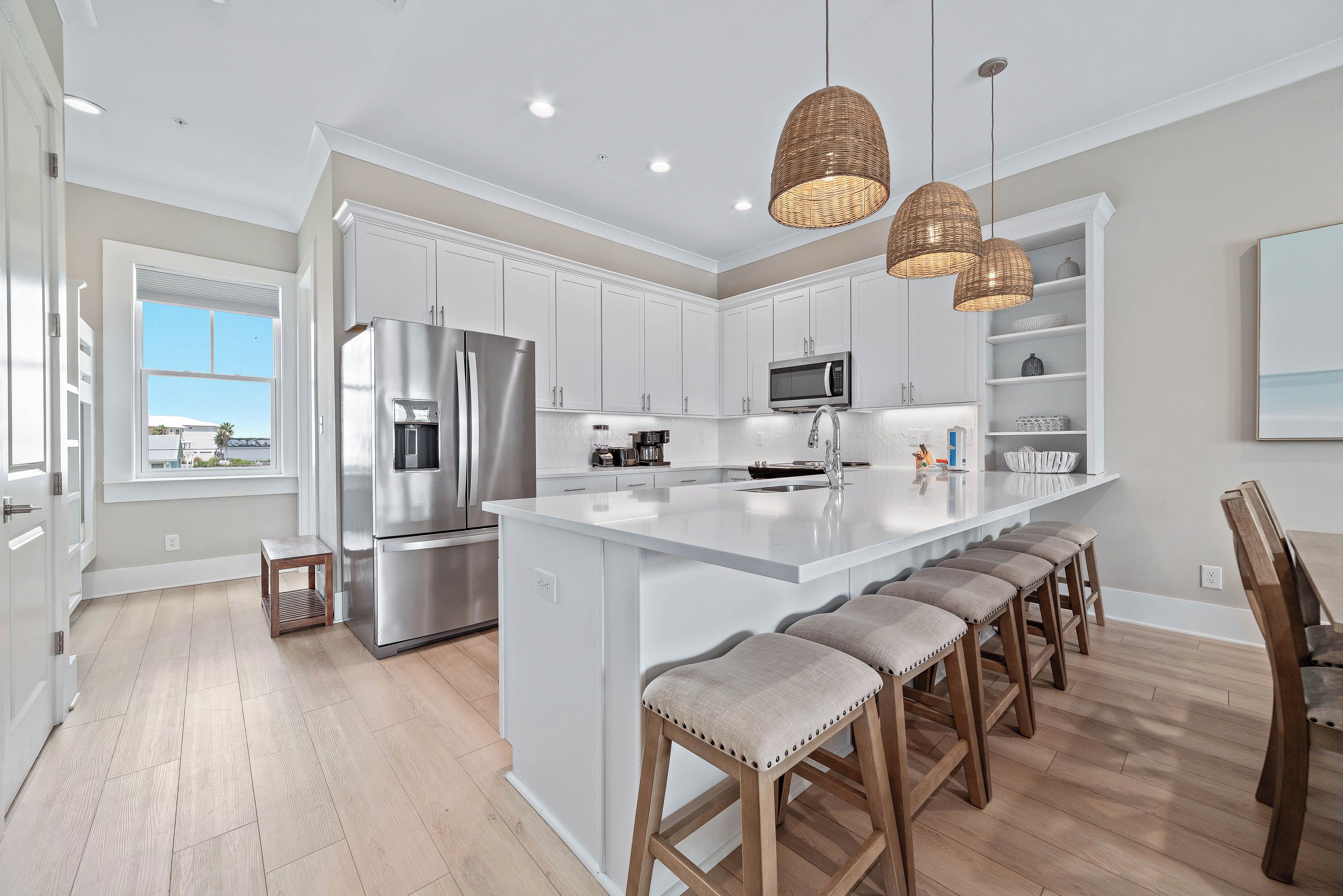 A modern kitchen with a large island, stainless steel appliances, and pendant lighting.