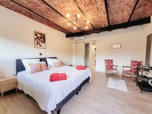 Une chambre avec un grand lit, un plafond en bois, une chaise et une petite table.