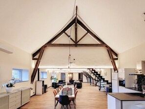 Une cuisine spacieuse équipée d’appareils modernes, un coin repas avec une longue table et un escalier menant à un autre niveau.