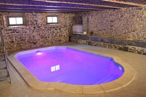 Une pièce aux murs de pierre, dotée d’un jacuzzi rectangulaire.