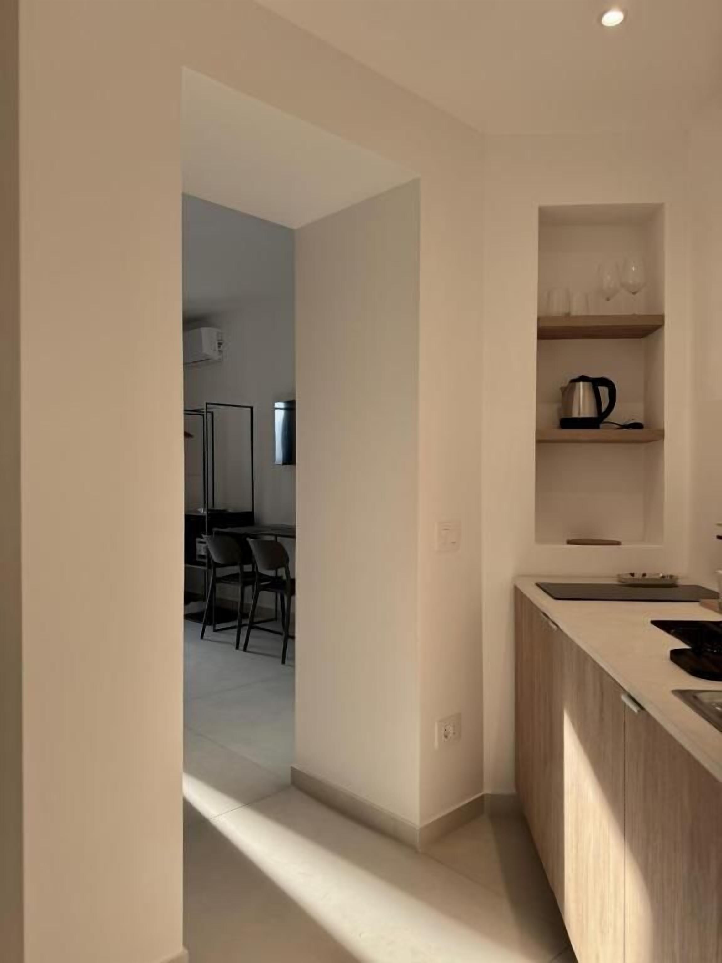 Una cocina moderna con encimera, pileta y estante con utensilios de cocina.