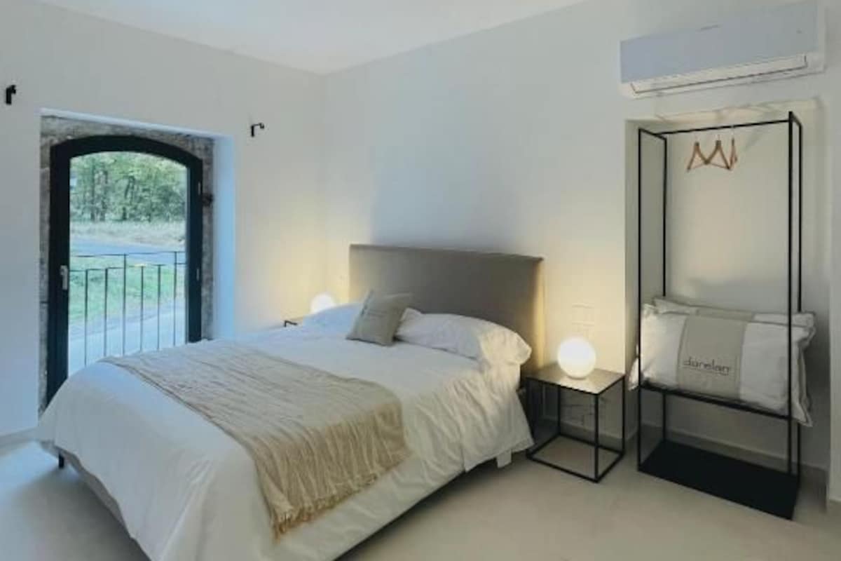 A bedroom with a bed, bedside table, and a chair.