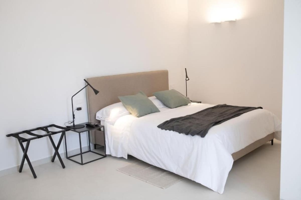 A bed with a headboard, a bedside table, and a lamp.