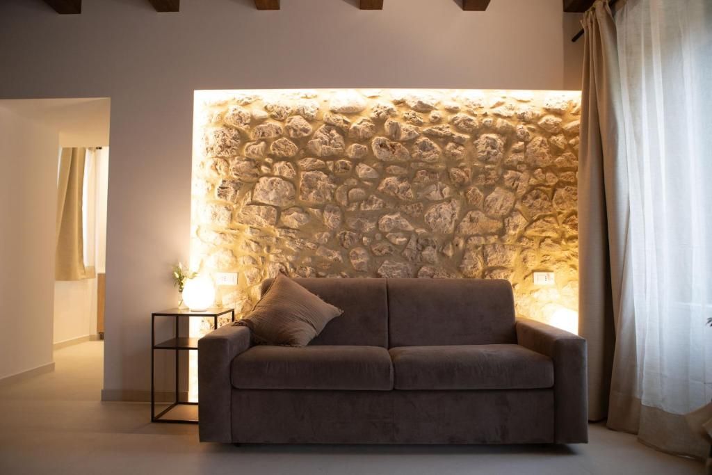 Una habitación con pared de piedra, un sofá, una mesita auxiliar y una lámpara.