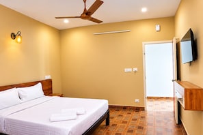 A hotel room with a bed, a ceiling fan, a wall-mounted TV, and a wooden cabinet.