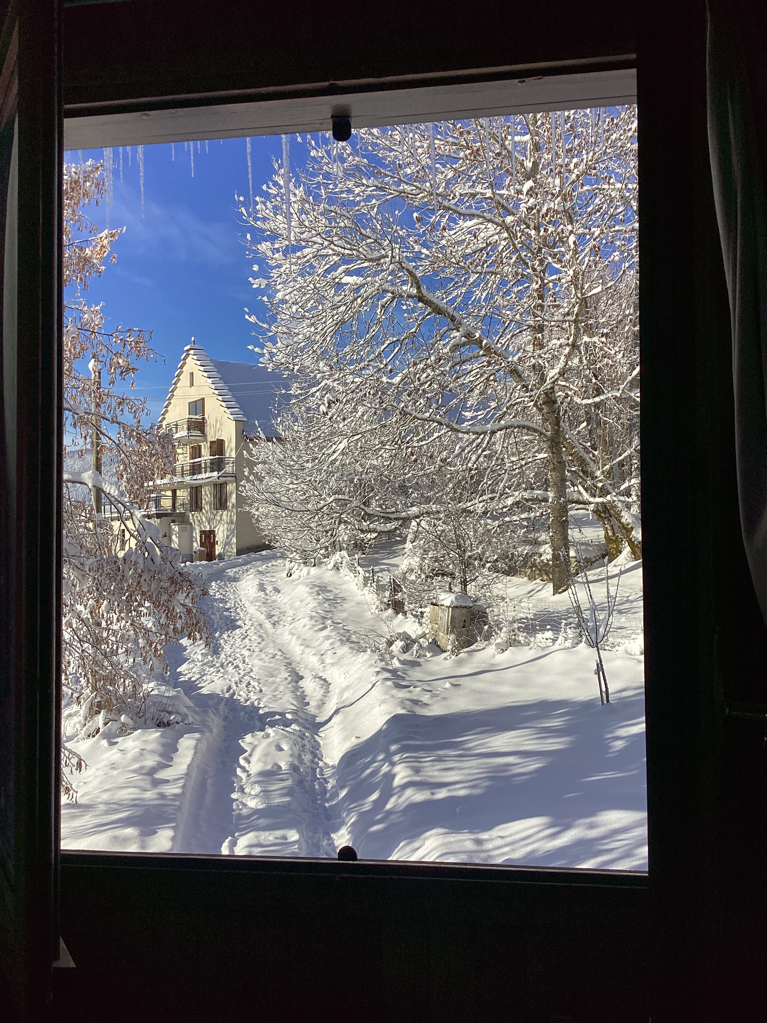 A snow-covered landscape with a building featuring a steep roof and a balcony.
