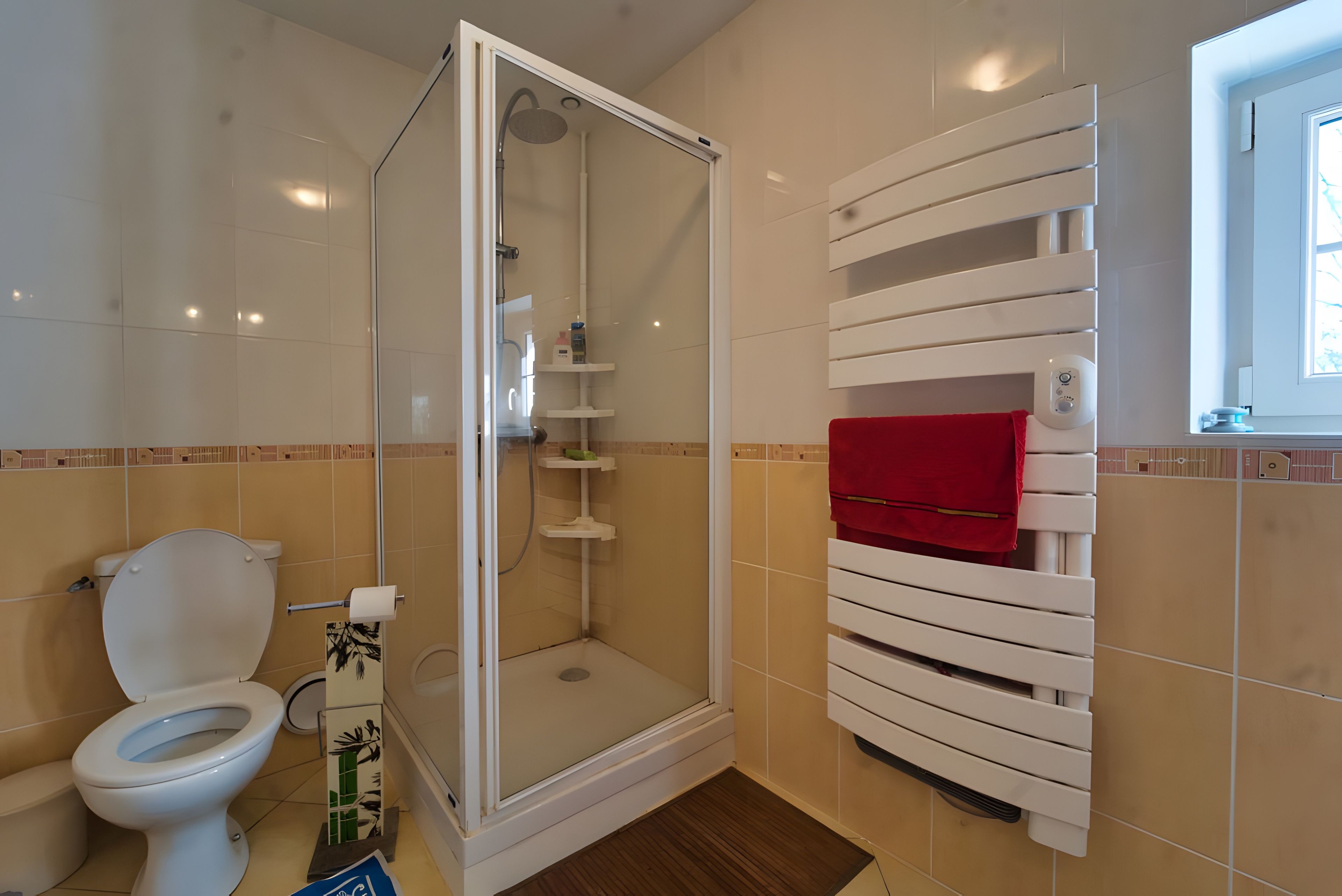 A bathroom with a toilet, a shower enclosure, and a towel rack.