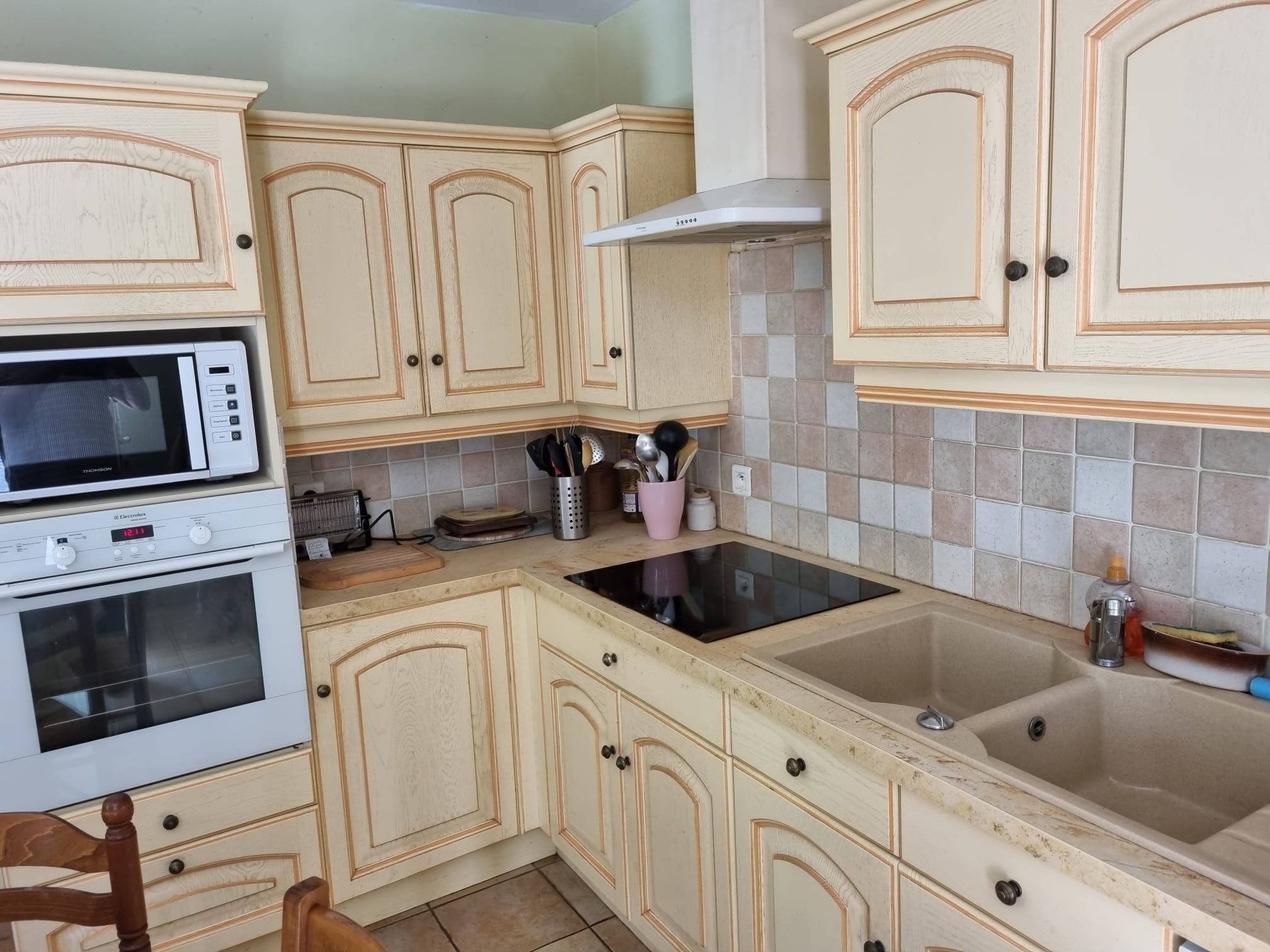 Eine Küche mit Holzausstattung, einer Mikrowelle, einem Backofen und einem Spülbecken.