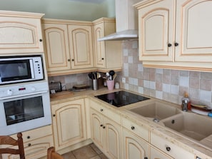 Eine Küche mit Holzausstattung, einer Mikrowelle, einem Backofen und einem Spülbecken.