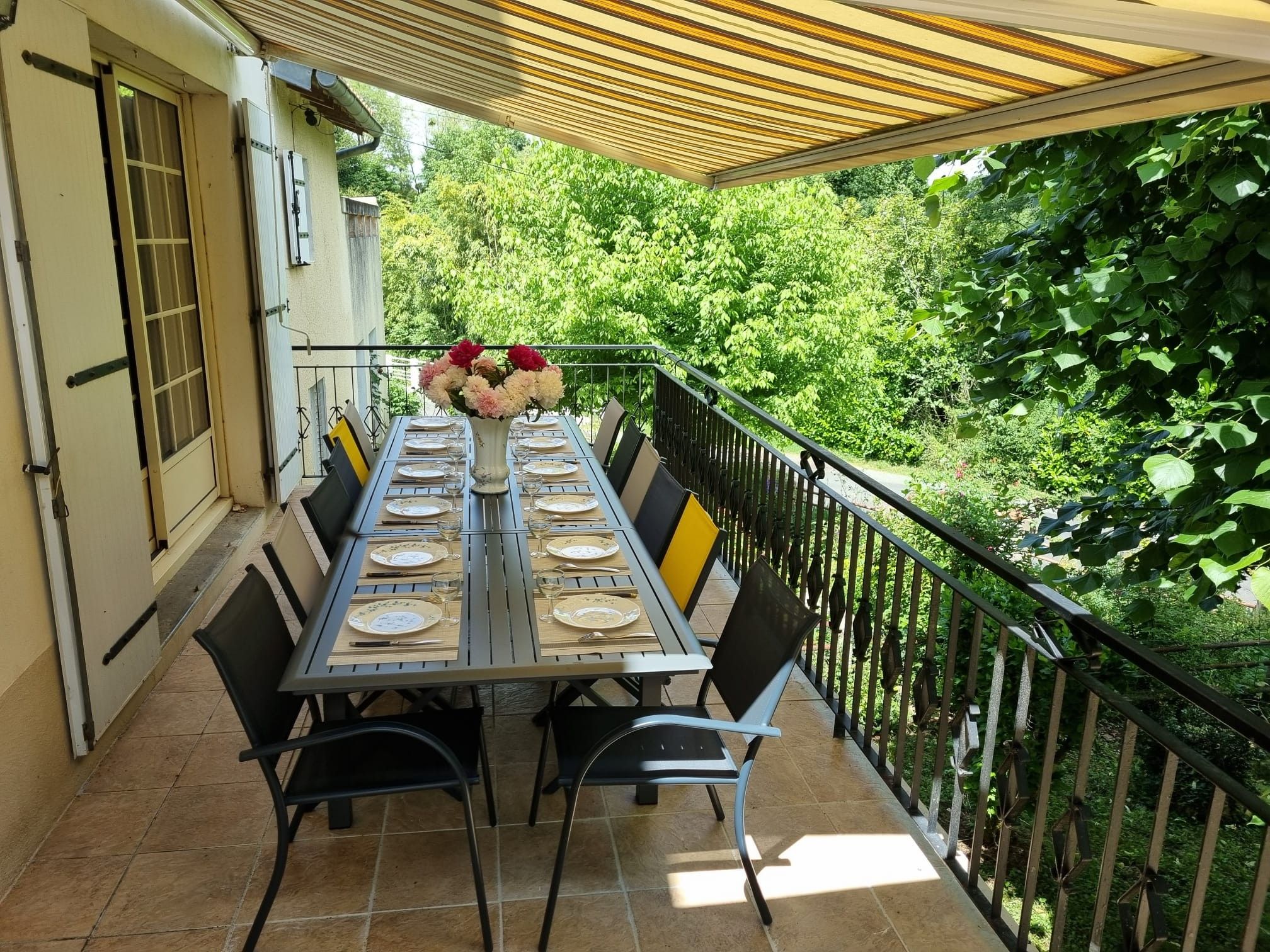Ein Essbereich im Freien mit einem Tisch für vier Personen, umgeben von Stühlen, unter einer beschatteten Pergola.