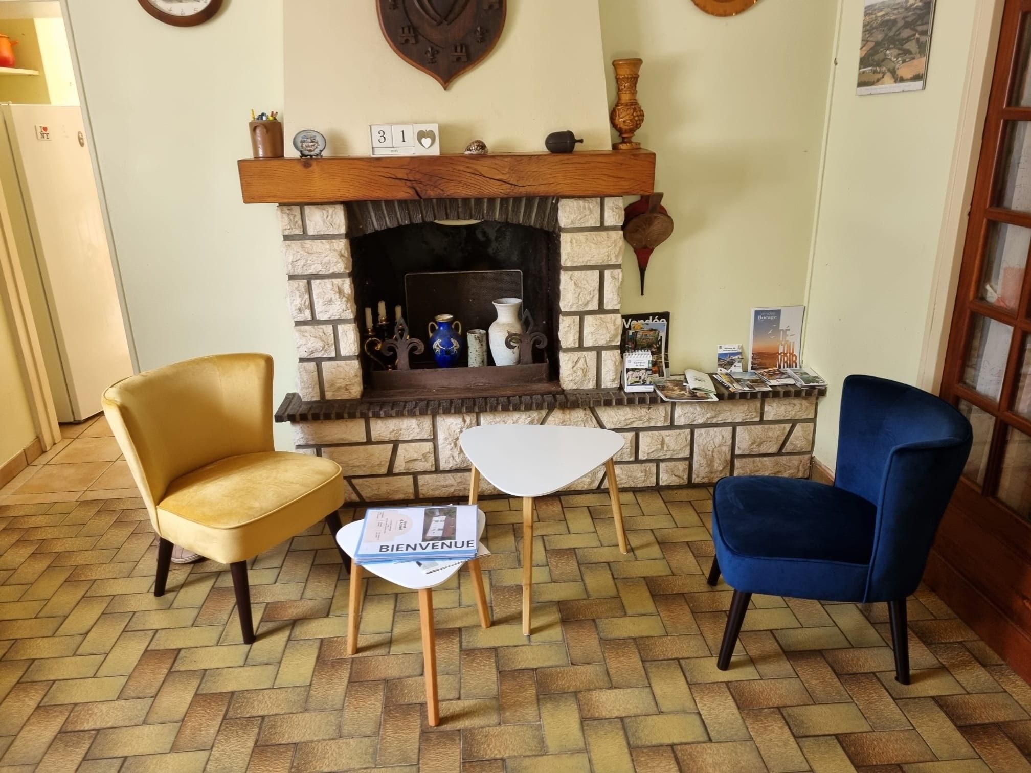 Una habitación con chimenea de piedra, dos sillones, una mesita y un folleto de bienvenida.