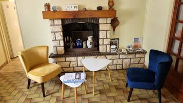 Una habitación con chimenea de piedra, dos sillones, una mesita y un folleto de bienvenida.
