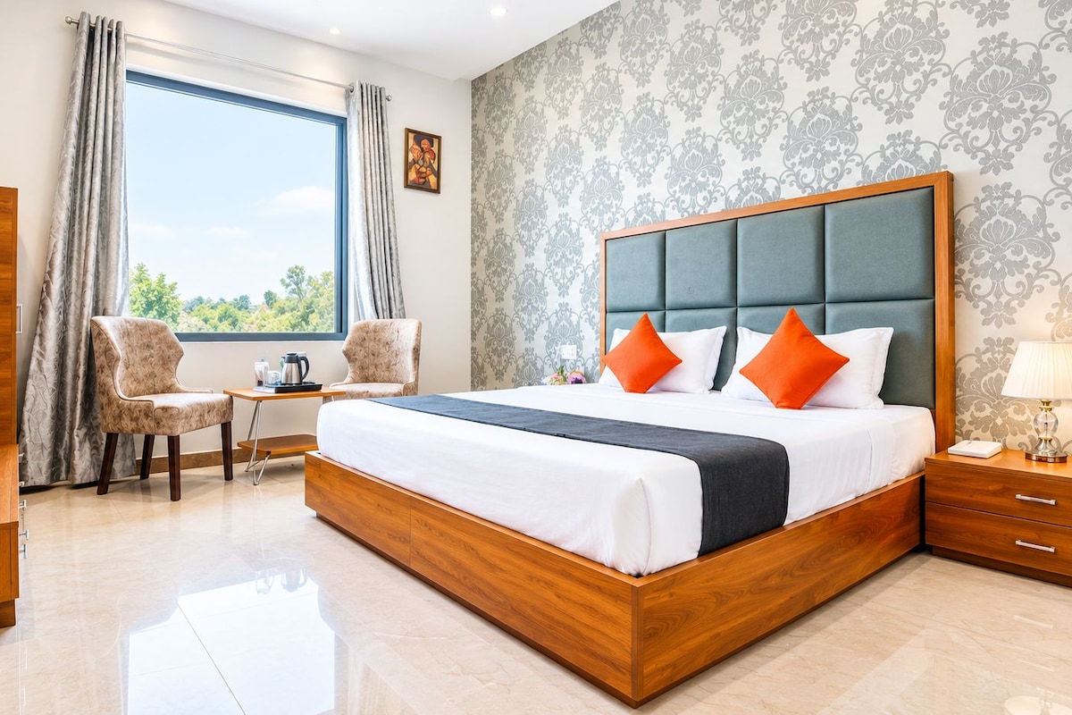 Habitación de hotel moderna con una cama grande, un escritorio y vistas al exterior.