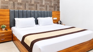 Una cama bien hecha con cabecera de madera, una mesita de noche con lámpara y una pequeña planta en maceta.