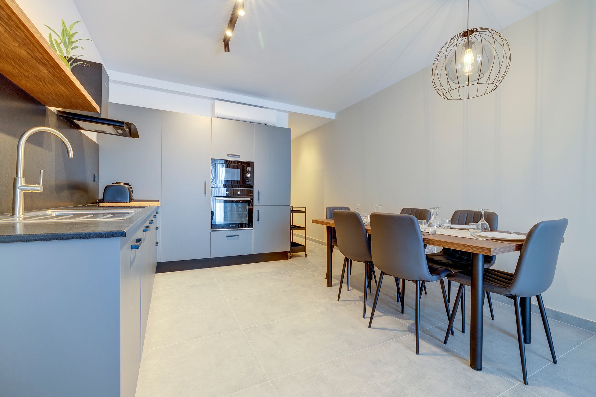 A modern kitchen with a built-in oven and a dining area with a table and chairs.