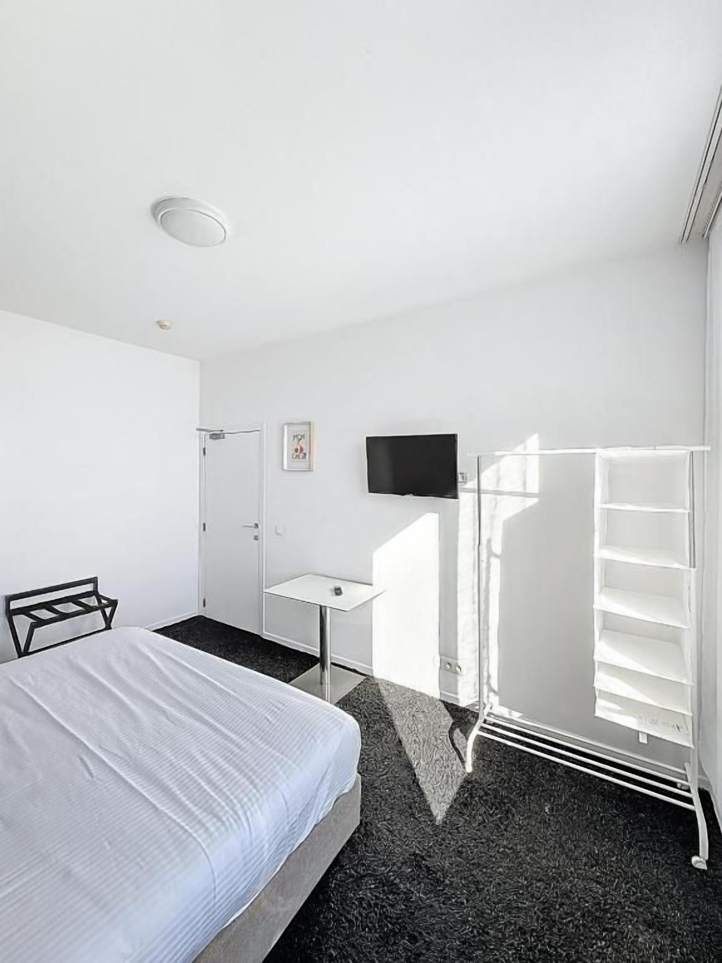 Une chambre d’hôtel équipée d’un lit, d’un bureau, d’une télévision et d’une armoire.