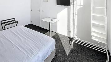Une chambre d’hôtel équipée d’un lit, d’un bureau, d’une télévision et d’une armoire.