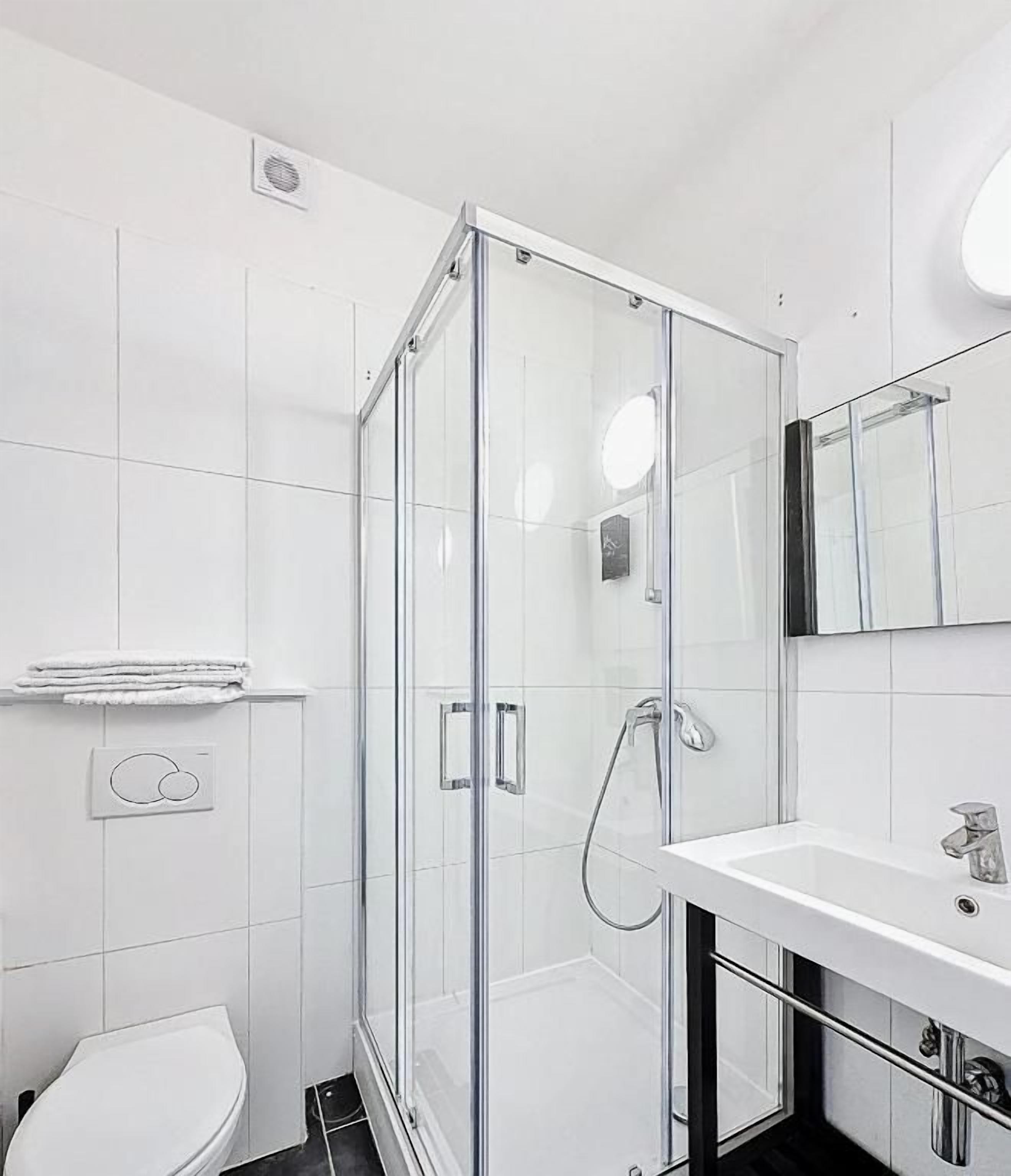 Une salle de bain moderne avec une douche à parois de verre, un lavabo blanc et des toilettes.