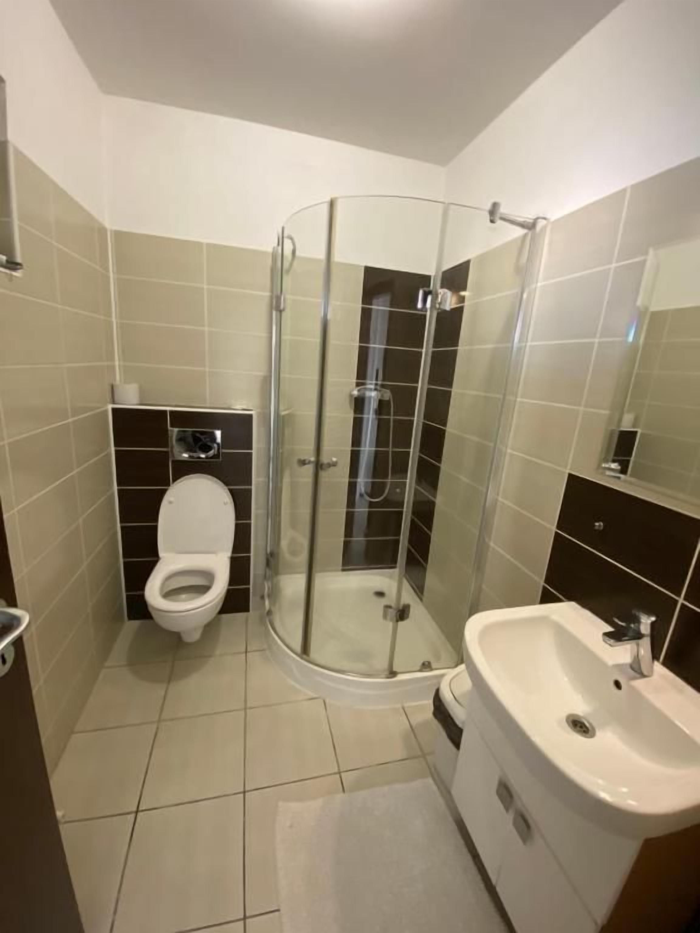 Un bagno con doccia vetro, WC e lavandino.