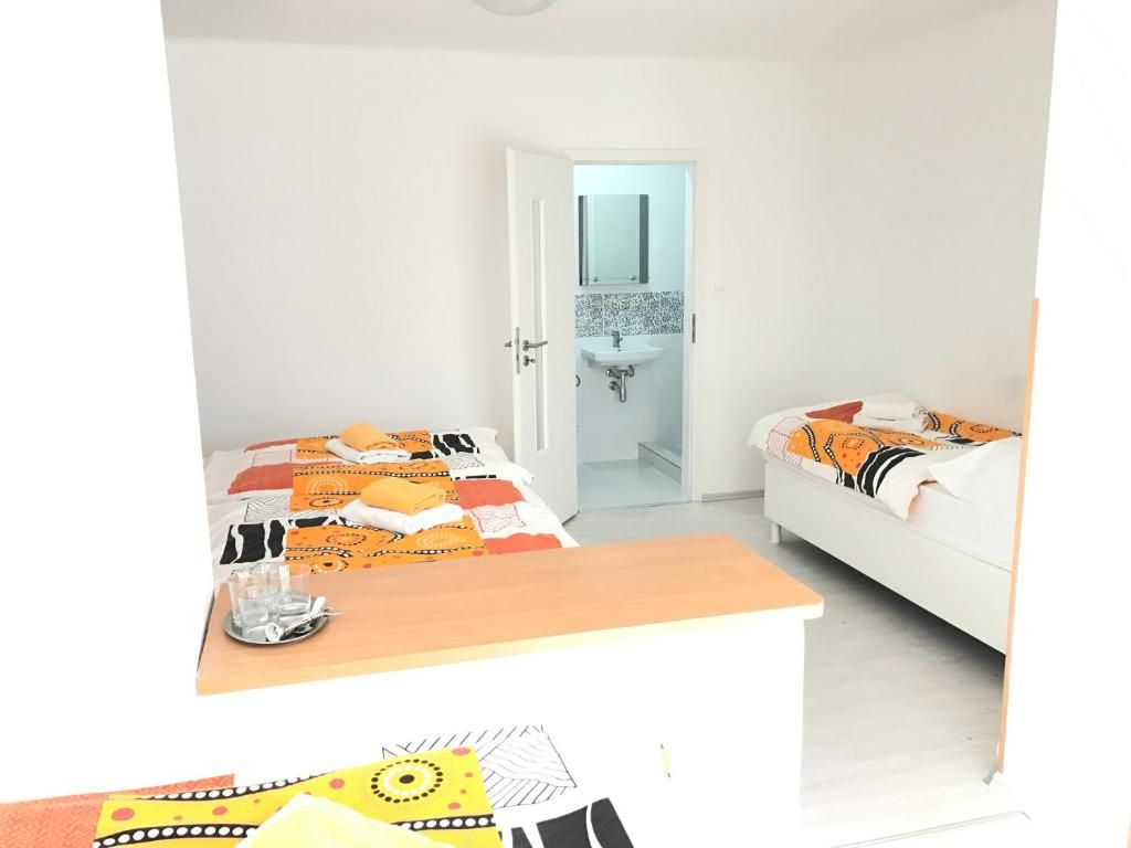 A bedroom with two beds, a bedside table, and a bathroom visible through an open door.