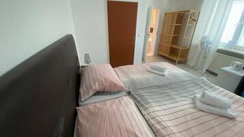 Un dormitorio con cama, armario y ventana con cortinas.