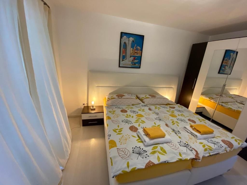 Una habitación de hotel con una cama, mesita de noche, lámpara y un espejo.