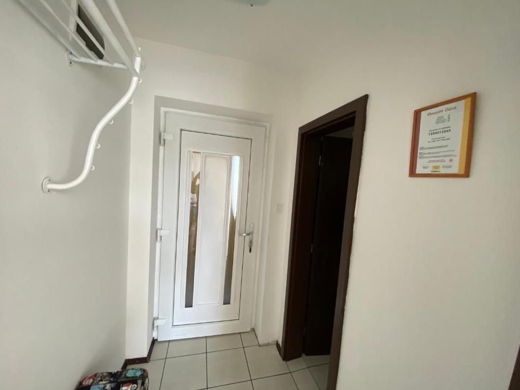 Un corridoio con una porta bianca, una porta scura e un certificato incorniciato appeso al muro.