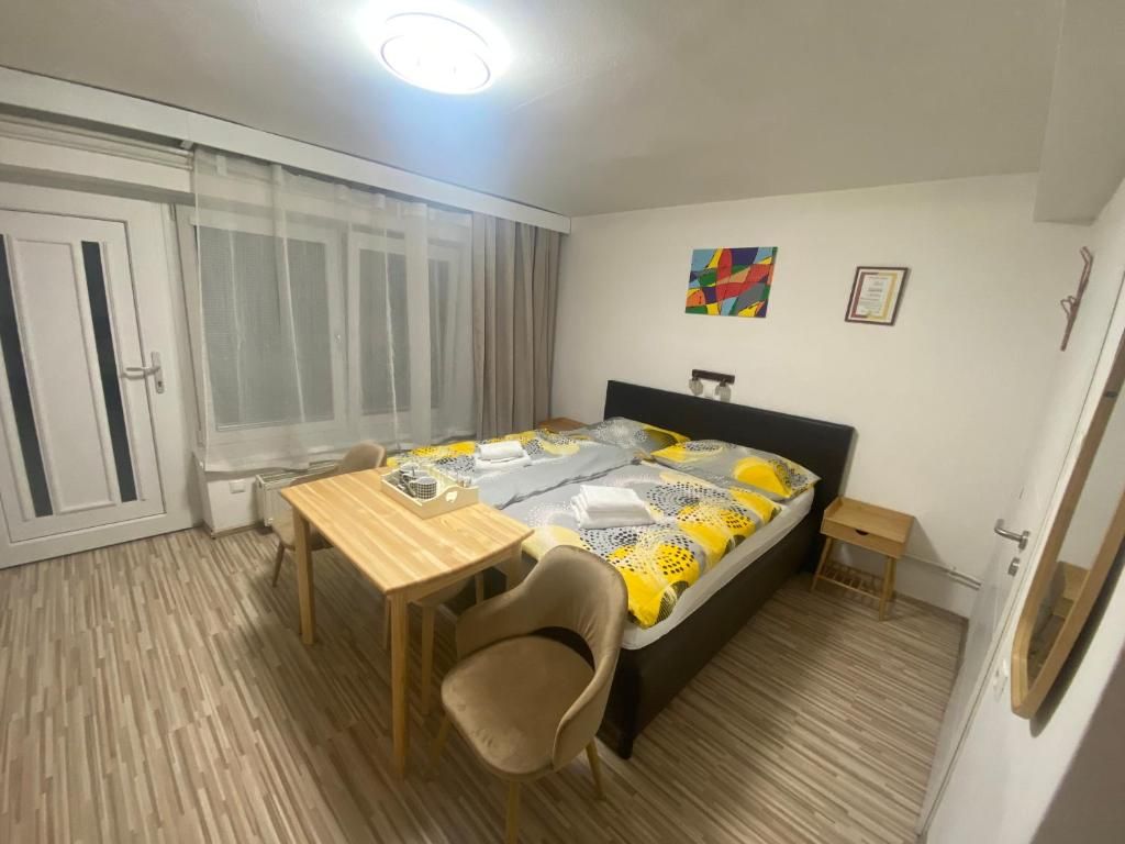 Quarto com cama, mesa, cadeira e janela com cortinas.