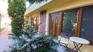 Un edificio con un camino pavimentado, una puerta, una ventana y una silla.