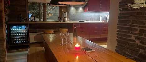 Un comptoir en bois avec une bougie allumée, un téléphone intelligent et des verres posés sur une table en bois.