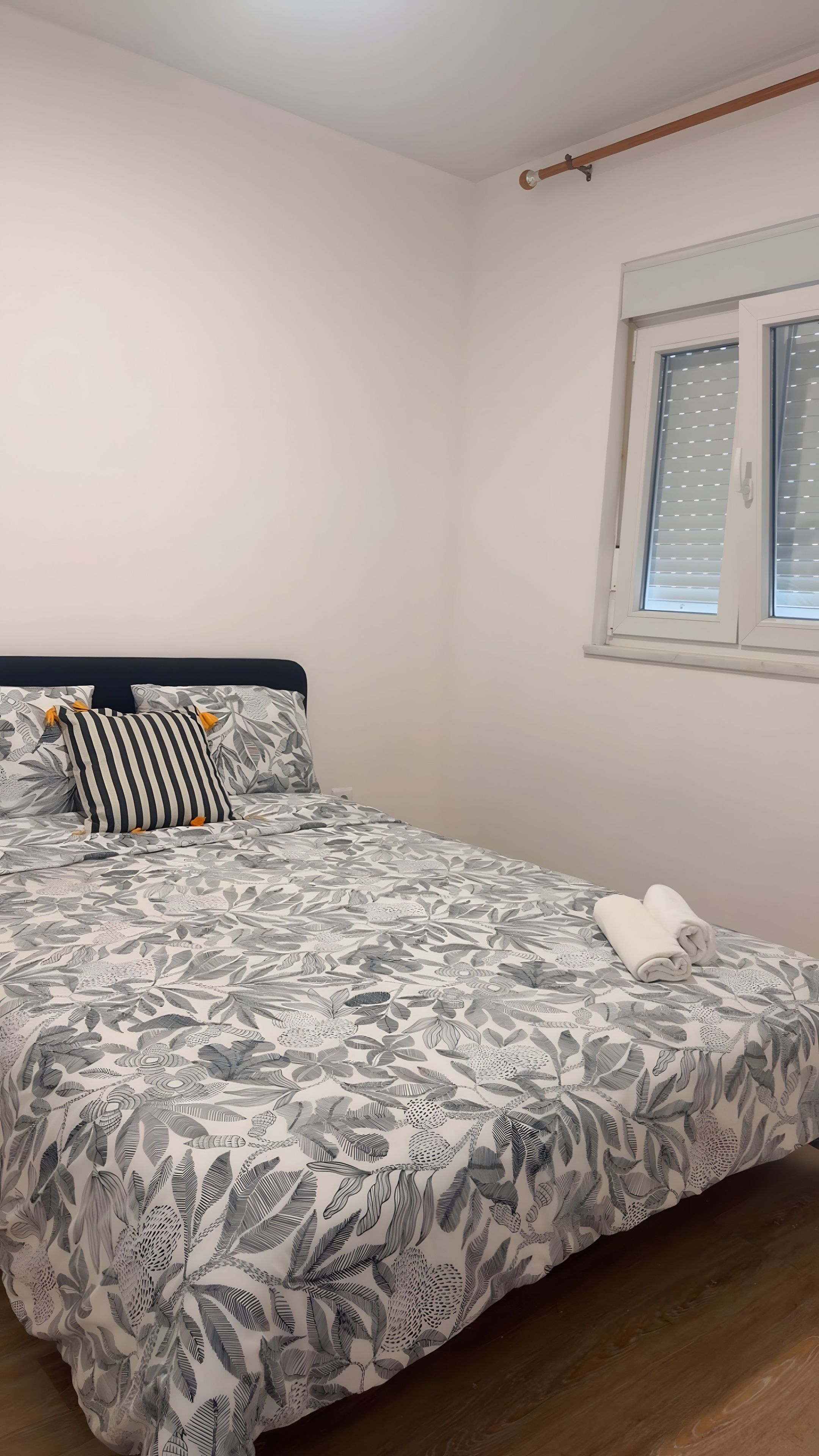 A bedroom with a bed, a window with blinds, and a wooden headboard.