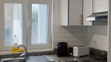 A modern kitchen with white cabinets, a granite countertop, a built-in oven, and a window providing natural light.