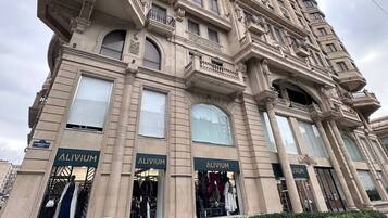Un immeuble à plusieurs étages, doté de balcons et de grandes fenêtres, avec des devantures de magasins arborant l’enseigne « ALIVIUM ».