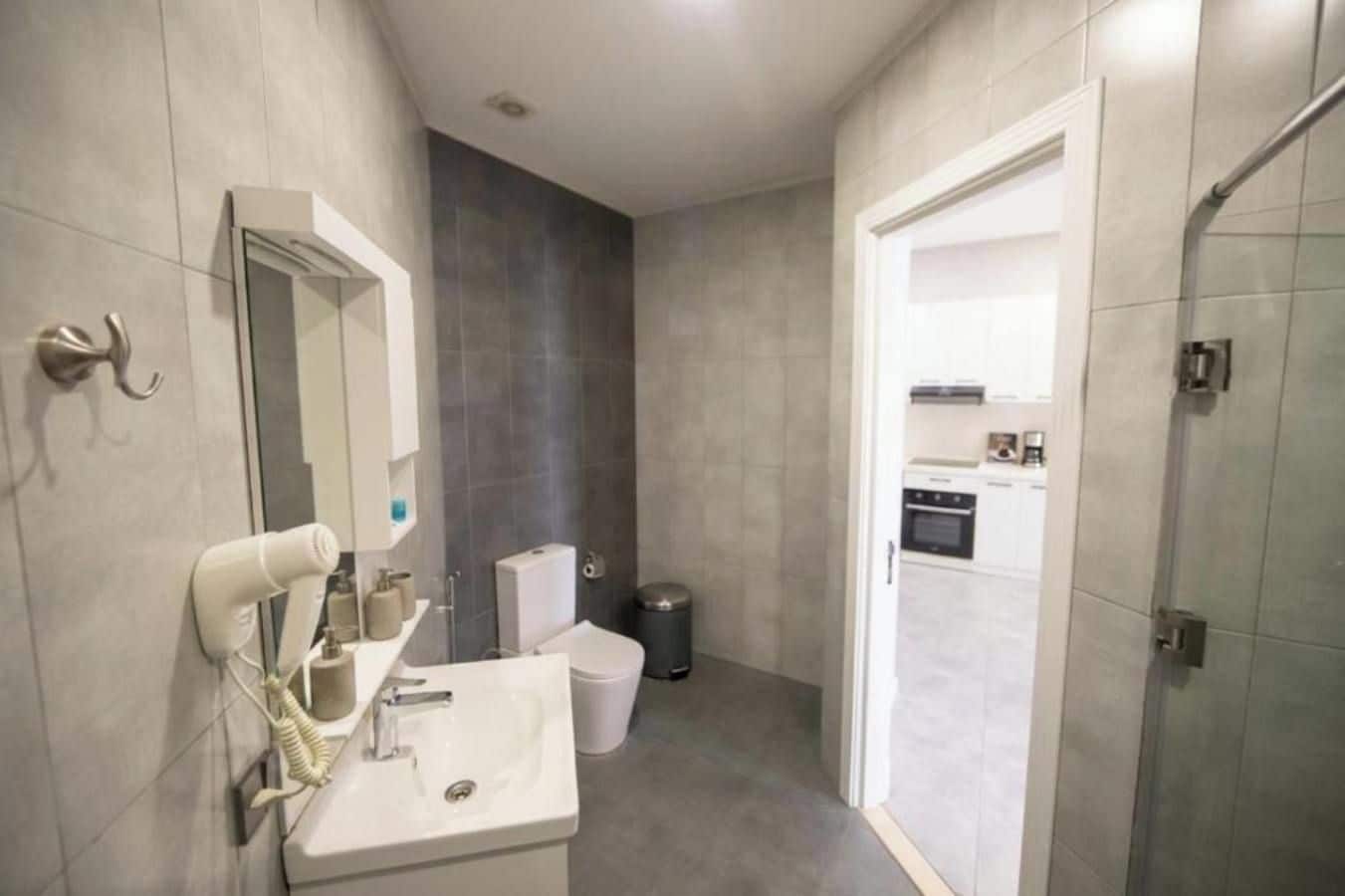 Un baño moderno con lavamanos, espejo y secador de pelo.