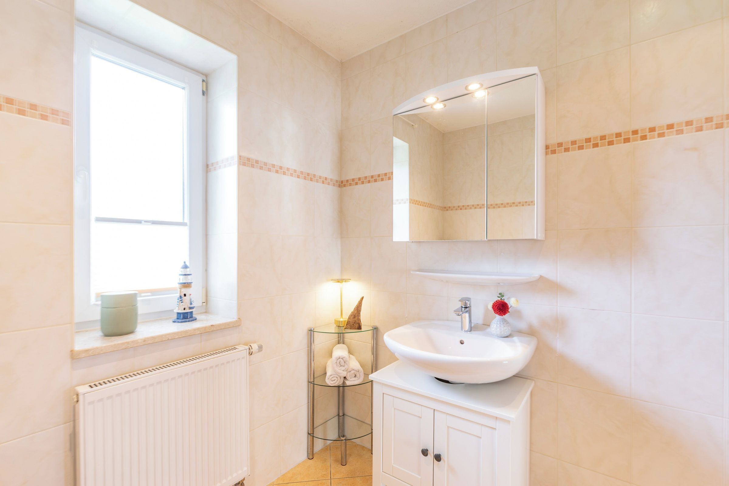 A bathroom with a window, a sink, a mirror, and a towel rack.