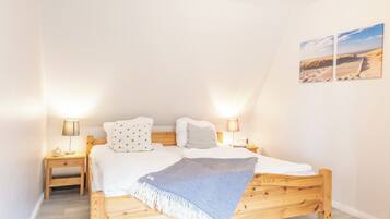 Une chambre à coucher avec un lit en bois, deux tables de chevet, une petite table et une lampe fixée au mur.