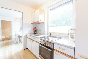 Una cocina moderna con armarios blancos, un lavamanos de acero inoxidable y un horno.