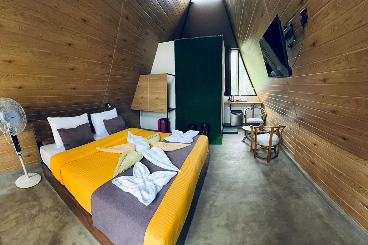 A compact room with a bed, a desk, a chair, and a fan.