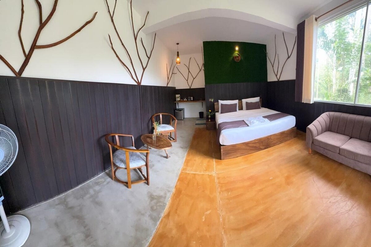 A modern bedroom with a bed, a sofa, a fan, and a dining area with chairs.