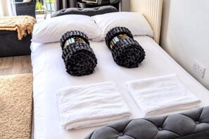 A bed with white linens, two rolled-up black towels, and a grey tufted headboard. - Modern 1-Bed Edgbaston  Free Parking  Birmingham (Birmingham)