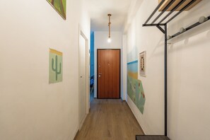 A hallway with a wooden door at the end, a ceiling light, and wall-mounted artwork. - Casa Libera Tra Mare e Foresta (Vico del Gargano)