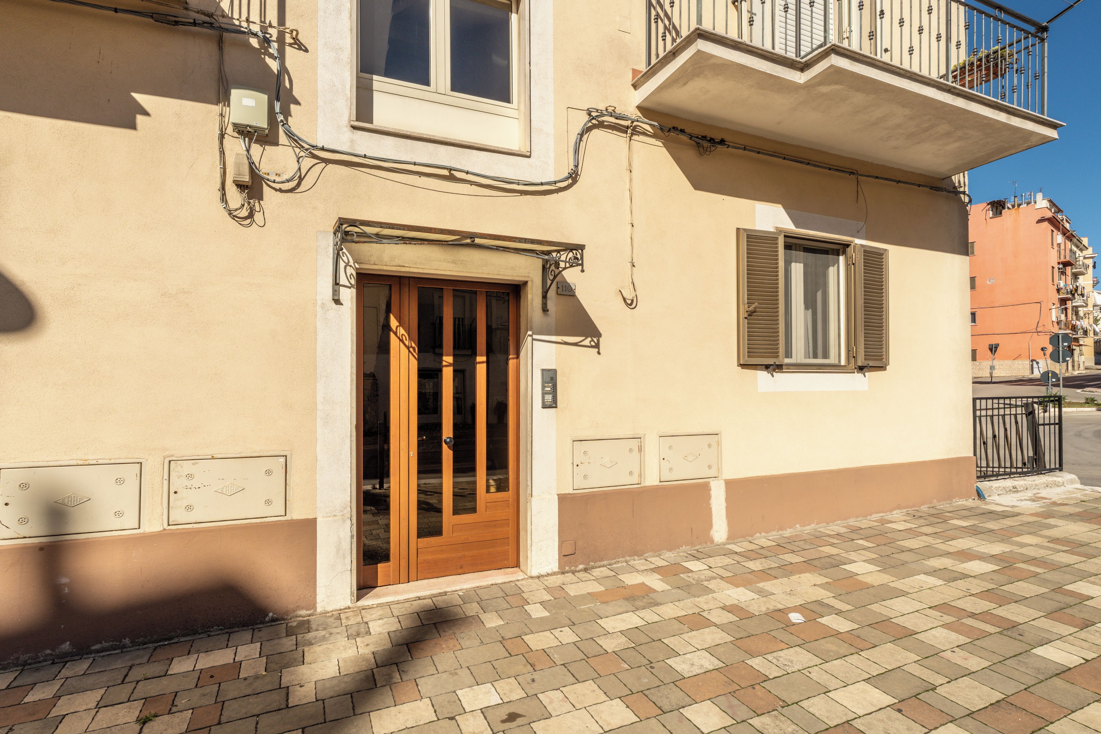 A building with a wooden door, a window with shutters, and a balcony with a railing.