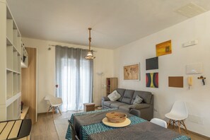 A modern living room with a sofa, a dining table, and a coffee table. There are bookshelves and a lamp. - Casa Libera Tra Mare e Foresta (Vico del Gargano)