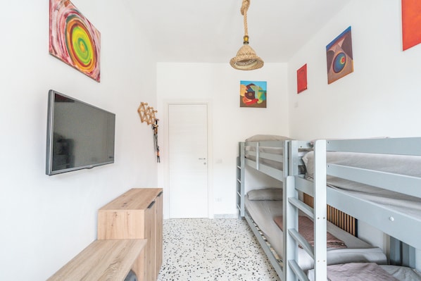 A room with bunk beds, a television, artwork on the walls, and a door. - Casa Libera Tra Mare e Foresta (Vico del Gargano)