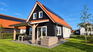 A modern house with a sloped roof, a covered patio, and a well-maintained lawn.