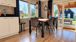 A modern kitchen with a dining area, large windows, and a view of the outdoors.