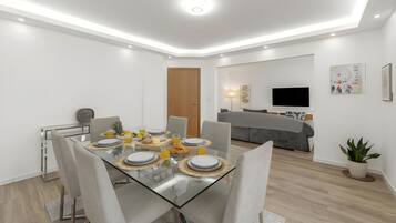 A modern dining area with a glass table, chairs, and a breakfast setting.